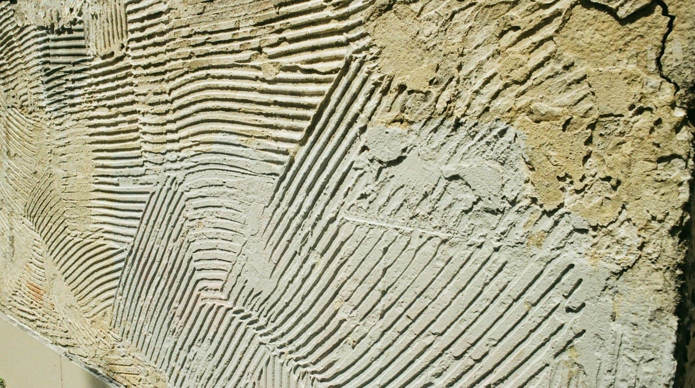 Illustrative photo: tile adhesive spread with a notched trowel